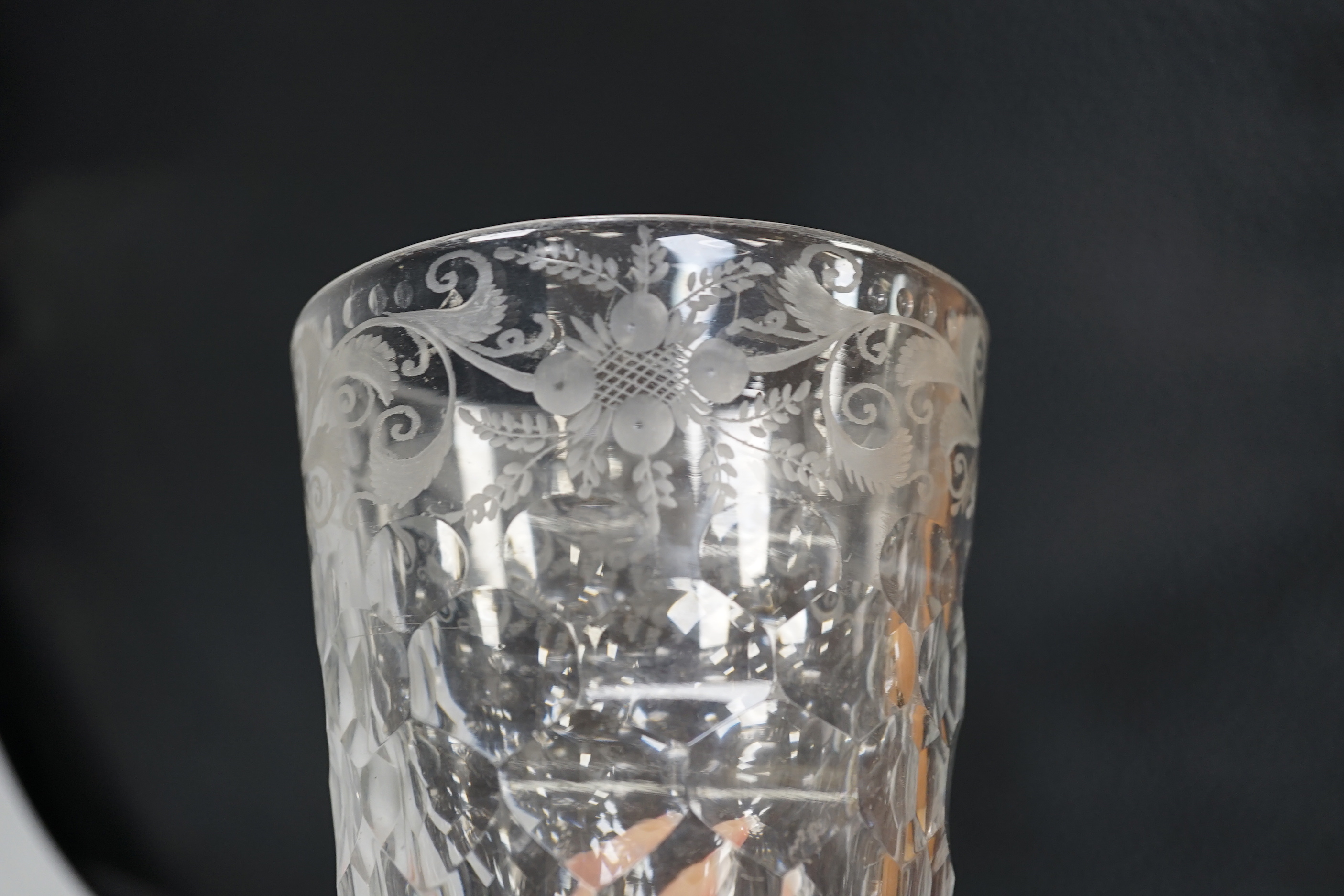 An English lead crystal 18th century faceted tumbler, in a darkish grey metal, upper decoration engraved and polished floral centre, three rows of facets running into plain facets, whole of foot polished to remove pontil